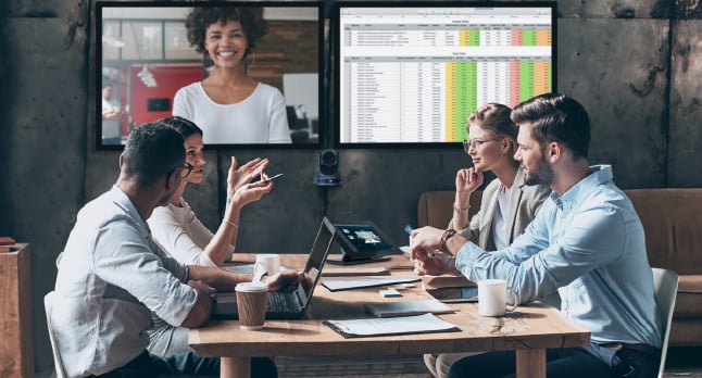Four employees sitting in a conference room partaking in a video conference call